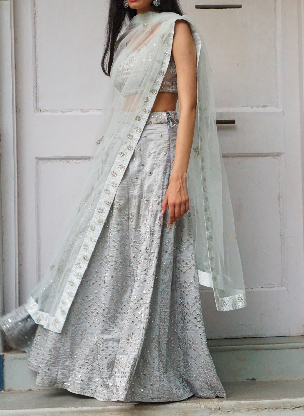 CREAM WHITE BANARASI GOTA WORK LEHENGA SET WITH A HAND EMBROIDERED MIRROR  WORK BLOUSE PAIRED WITH A MATCHING RUFFLED DUPATTA AND GOLD DETAILS. -  Seasons India